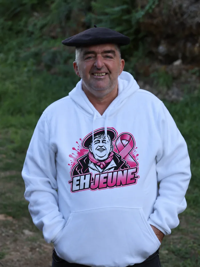Pull blanc EH JEUNE Octobre Rose, logo et ruban rose, porté par Frédéric Fraysse
